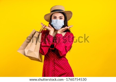 Portrait of young happy carefree asian woman wear hat and facemask carrying shop bag smile on isolated color background in concept back to shopping, new normal summer fashion lifestyle after covid19. Royalty-Free Stock Photo #1760754530
