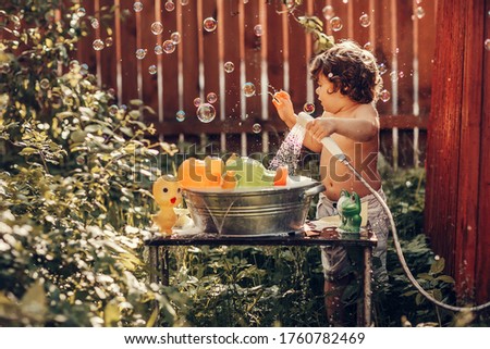 A boy washes toys in the garden in a basin