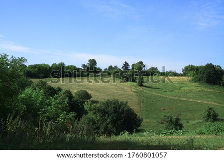 Beautiful summer landscape of nature countryside. Green vegetation of grass and trees with hills. Stock photo for design