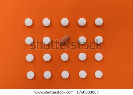 Stock photo of a bunch of pills placed in order on an orange background. There is nobody on the picture.