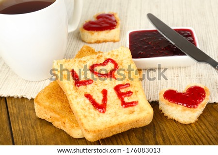 Delicious toast with jam and cup of tea on table close-up