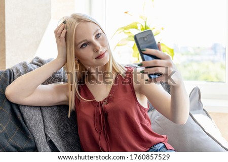 blonde girl takes a selfie while sitting on a sofa