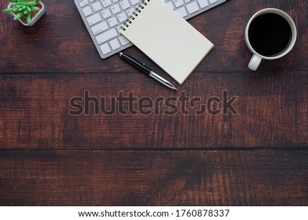 Wood office desk table with keyboard, notebook and coffee cup, pen with equipment other office supplies. Business and finance concept. Flat lay with blank copy space.