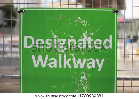 Green designated walkway sign with white letters