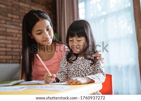 sister help her little sibling to learn and study homework while staying home