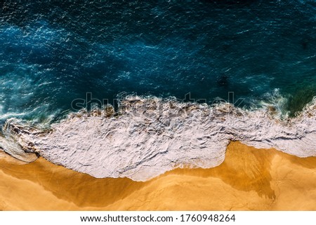 Beautiful sandy beach at sunset. Beach with yellow sand and sea foam. The sea wave covers the sandy beach with yellow sand at sunset. Aerial photography of the beach. beautiful Wallpaper. Copy space