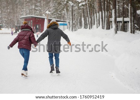 Couple man and woman on ice skating rink in winter. Back view.