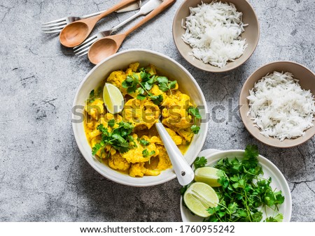 Indian food table - vegetarian cauliflower curry sauce, rice, cilantro, lime on grey background, top view         Royalty-Free Stock Photo #1760955242