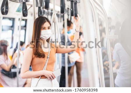 Young Asian woman passenger wearing surgical mask and listening music via smart mobile phone in subway train when traveling in big city at Covid19 outbreak, Infection and Pandemic concept
 Royalty-Free Stock Photo #1760958398