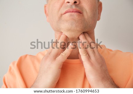 Mature man checking thyroid gland on grey background, closeup Royalty-Free Stock Photo #1760994653