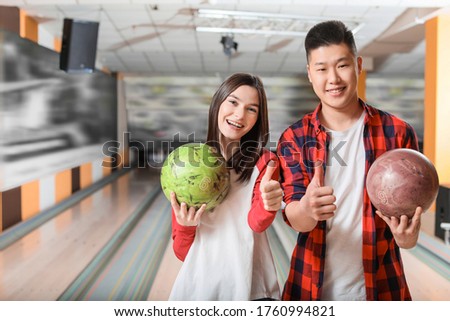 Portrait of friends showing thumb-up in bowling club