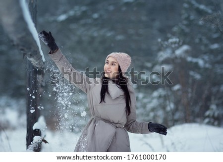 Portrait of a girl with snow matting with a wooden febce. Image with selective focus and toning.