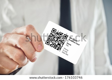 Businessman holding QR code business card with personal data. Modern technology concept.