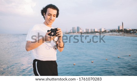 Caucasian tourist adjust settings on modern camera for photographing environment and practicing skills,young amateur with technology equipment editing pictures during free time near seashore