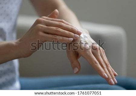 Close up view young woman sitting indoor applying moisturizing nourishing cream for hands. Organic beauty cosmetics natural oil product advertisement, daily treatment for beautiful smooth skin concept Royalty-Free Stock Photo #1761077051
