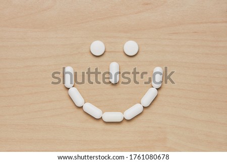 Smile tablets and capsules on wooden background. Health care concept
