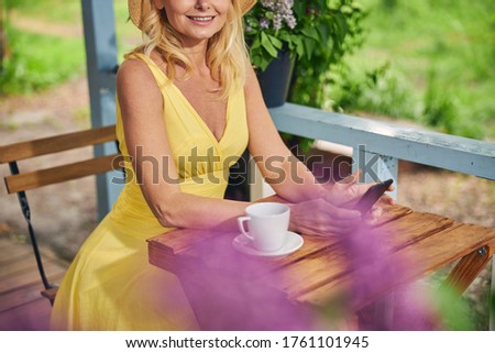 Cropped photo of a stylish blonde woman relaxing during the tea break on the veranda
