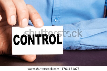A man holds in his hand a card with the written word CONTROL