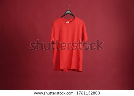 Exclusive hanger with empty red t-shirt hanging isolated on a red background. Blank red male tshirt template, from two sides, for your mockup design to be printed.