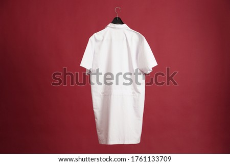 Exclusive hanger with empty doctor clothes hanging isolated on a red background. Blank doctor male tshirt template, from two sides, for your mockup design to be printed.	