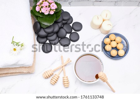 Honey in a bowl with some towels and some flowers on a marble table. Skin care and beauty treatment concept