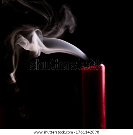 Red candle billows smoke after being extinguished.