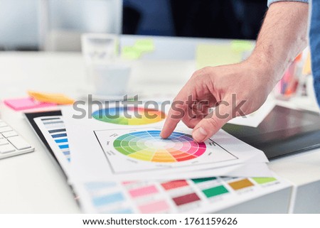 Hand of web designer points to the color palette in web development