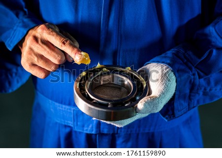 Mechanic is putting lubricant grease into ball bearing in the industrial factory, Technician Industrial Concept Royalty-Free Stock Photo #1761159890