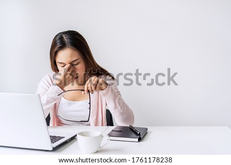 Tired and stressed young asian woman feel pain eyestrain and rubbing her eyes and take off her glasses while sitting at her working place  Royalty-Free Stock Photo #1761178238