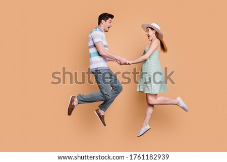 Full length profile photo of attractive lady handsome guy funny married couple jumping high up good mood holding hands in love wear summer clothes isolated beige color background