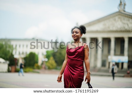 Portrait of a beautiful natural young African woman with afro hair. Black model in red silk dress.