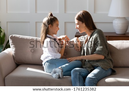 Caring mother and little daughter chatting, sitting on cozy couch in living room, pretty girl sharing secrets with loving mum, having pleasant conversation, good trusted family relationship Royalty-Free Stock Photo #1761235382