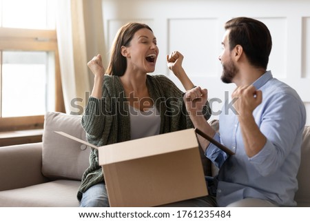 Excited overjoyed man and woman unpacking awaited parcel together, happy young couple celebrating success, lottery winner prize, satisfied clients customers received order, good delivery service Royalty-Free Stock Photo #1761235484
