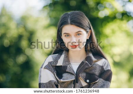 Closeup portrait of pretty girl with long hair on trees background. Attractive young woman enjoying her time outside in trees with sunset in background. Portrait closeup face looking camera