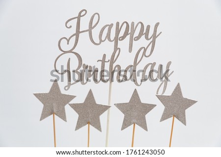 Happy Birthday written in silver letters with star shapes. Isolated on white background. Close-up.