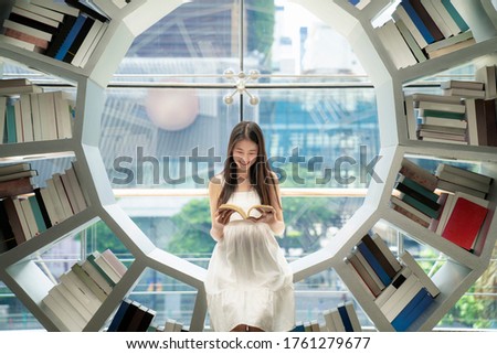 Asian girl reading on a bookshelf in a library in her university