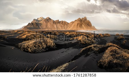 Vestrahorn mountains and Stokksnes beach near Hofn, southern Iceland. Grasses and black vocanic sands at low tide during golden hour. Royalty-Free Stock Photo #1761287858