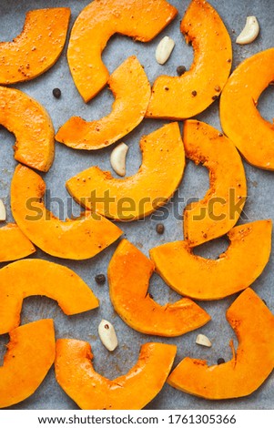 Many bright slices of pumpkin prepared for baking in the oven.