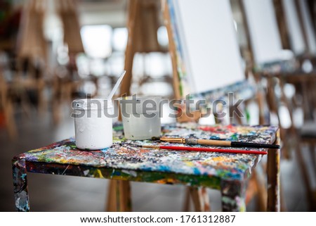 Easel, art brush, canvas for painting, paints, paintings well placed in art school