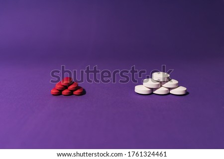 Stock photo of two piles of different pills placed on a purple background. There is nobody on the picture.