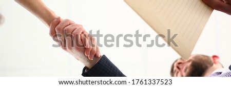 View from below of man and male shaking hands as hello sign of future collaboration prospects closeup