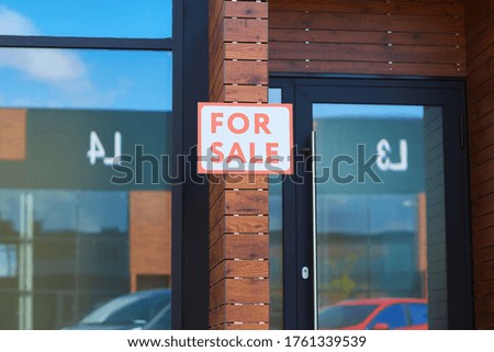 Image of modern office building with placard For Sale hanging on the brick wall