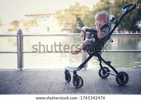 little boy sat in a stroller resting beside the pool at sunset.