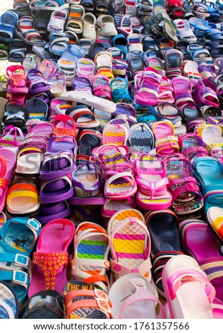 Summer multicolor footwear (no name, no brands). Flip-flops and sandals on the market. Vertical image