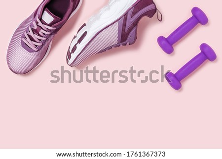 Sneakers and dumbbels on pink background. Flat lay picture with space for text,