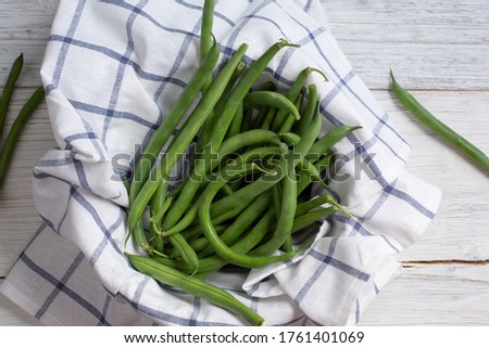 A top down view of a haricot vert, French green beans, in a bowl, in a still life setting.