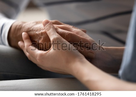 Nurse caregiver or grown up daughter granddaughter holding hand of elderly mother grandma or patient express care close up view, relative overcome together through life troubles disease griefs concept Royalty-Free Stock Photo #1761418295