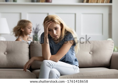 Young nanny rest on couch feels tired and annoyed does not cope with capricious little kid girl. Preschool daughter driving crazy with noise and screams and hyperactivity her exhausted mother concept Royalty-Free Stock Photo #1761418658