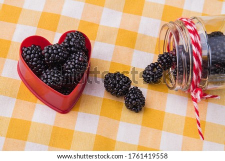 Blackberries in a heart shape. Yellow checkered background.