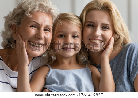 Close up concept image beautiful faces or 3 generations multi-generational relatives women portrait. Little granddaughter pose between old grandmother and young mother family smiling looking at camera Royalty-Free Stock Photo #1761419837